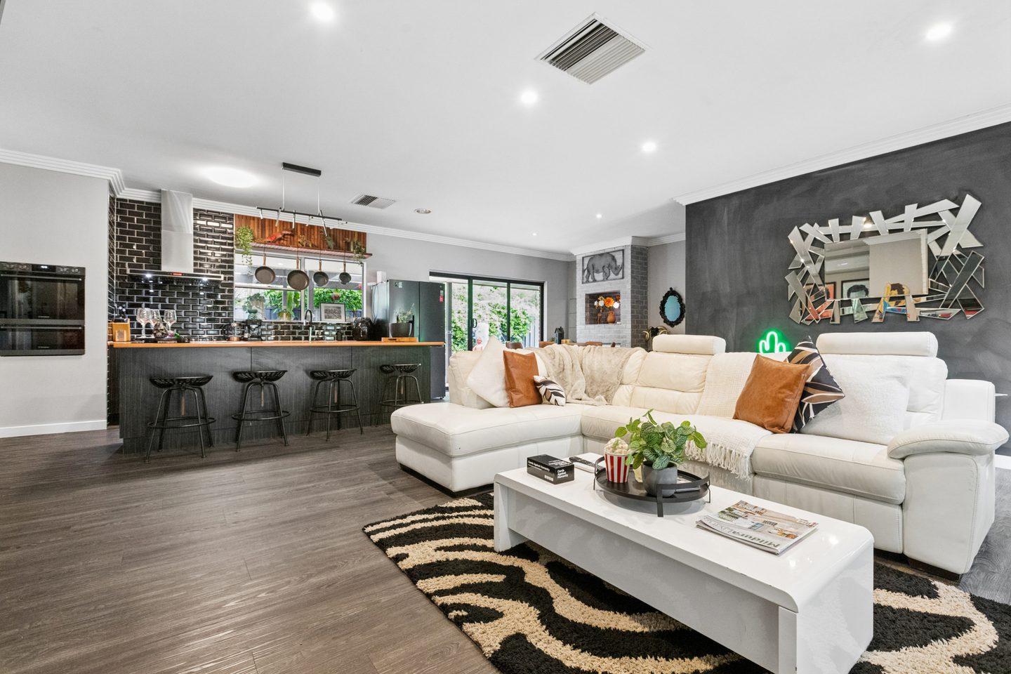 Open living area with a dark feature wall and black-tiled kitchen