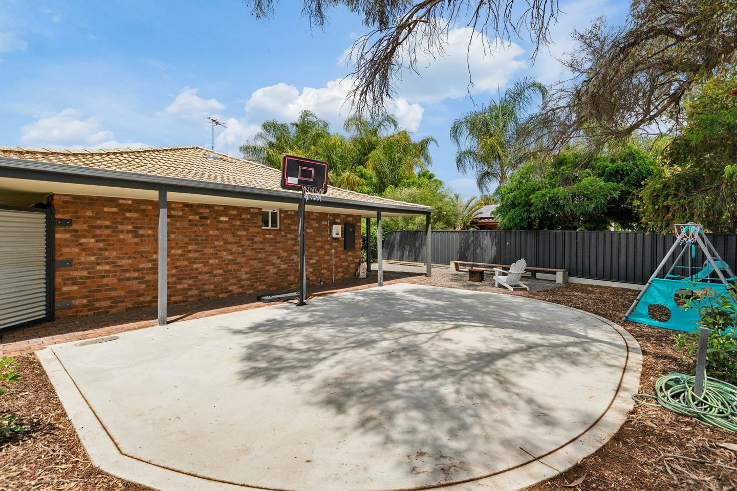Half basketball court alongside the house, with the firepit area beyond